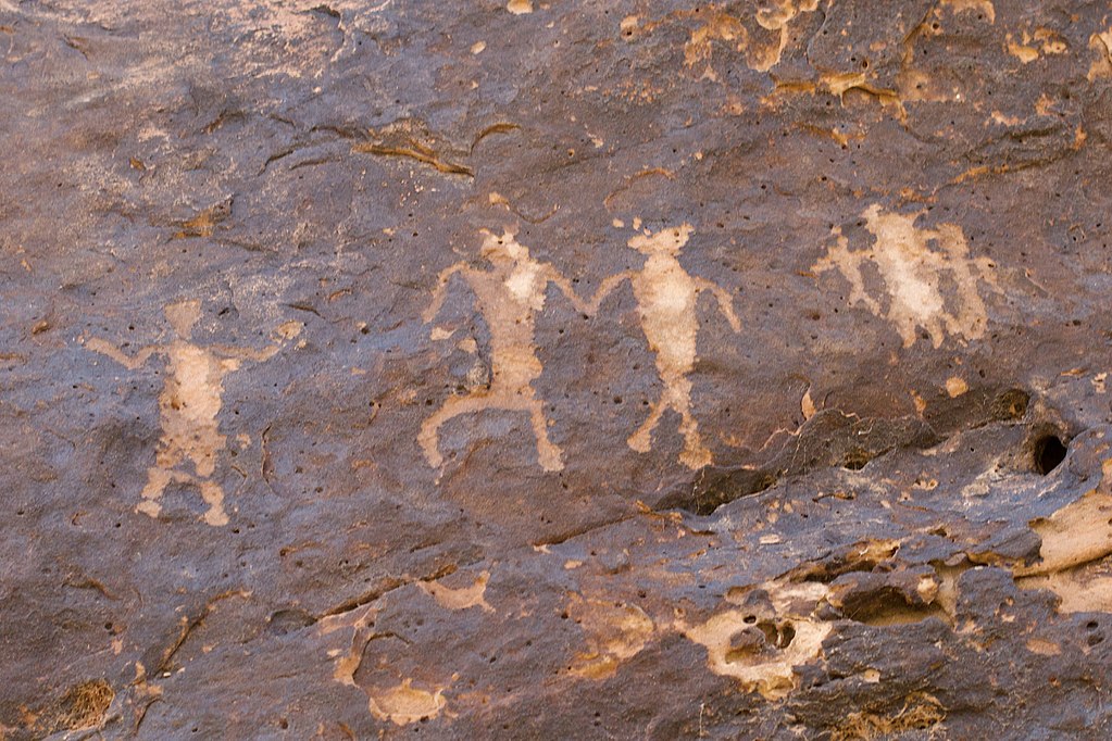 hieroglyphs of people holding hands on brownish rock
