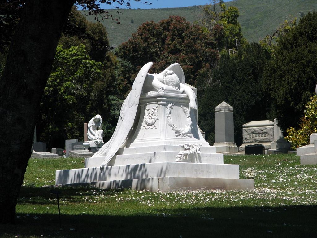 stone statute of angel slumped and crying atop a tomb