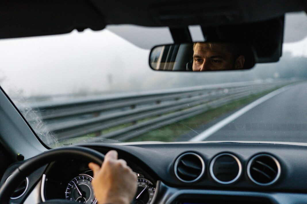 man looking in rearview mirror